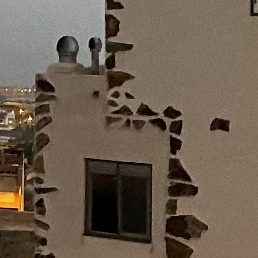 A white wall with stones and a window, taken by phone A